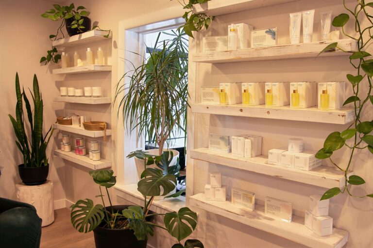 Aftercare and skincare products on white shelves surrounded by plants at Wax & Lash Berkeley in Denver