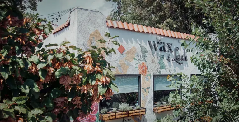 Exterior of Wax & Lash Berkeley in Denver with the studio sign and painted floral mural