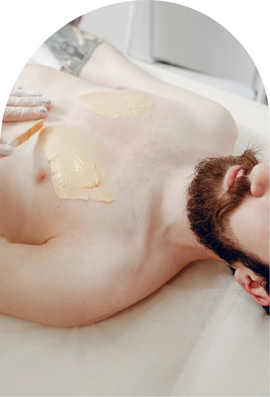 An esthetician applying soft wax to a man's chest during a men's waxing appointment in Denver